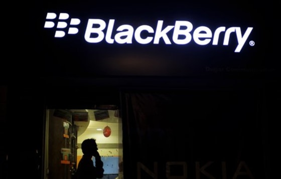 A man chats on his mobile as he walks past the hoarding of BlackBerry mobile in Ahmadabad, India. 